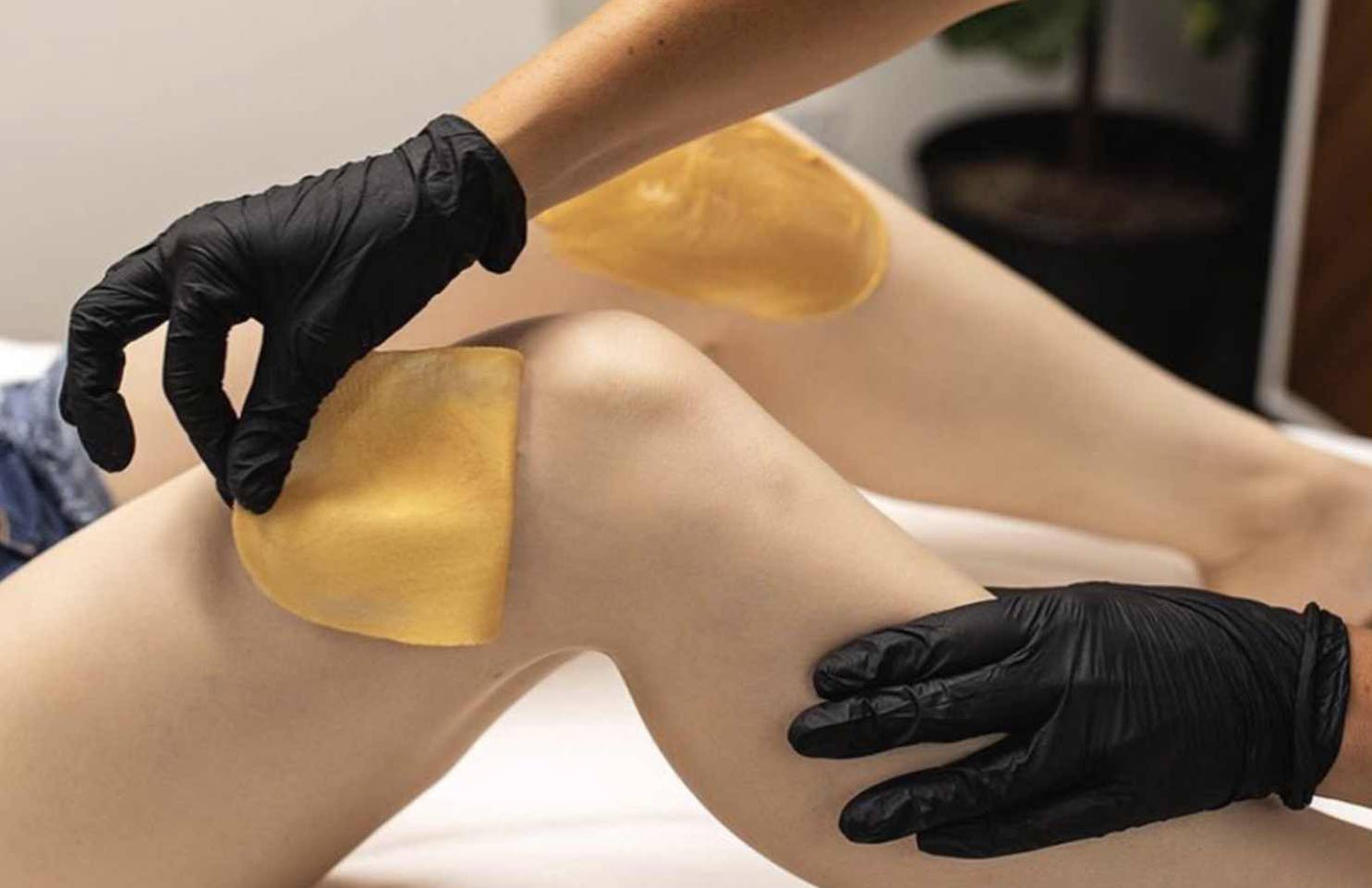 Mano che depila gamba con cera dorata italwax